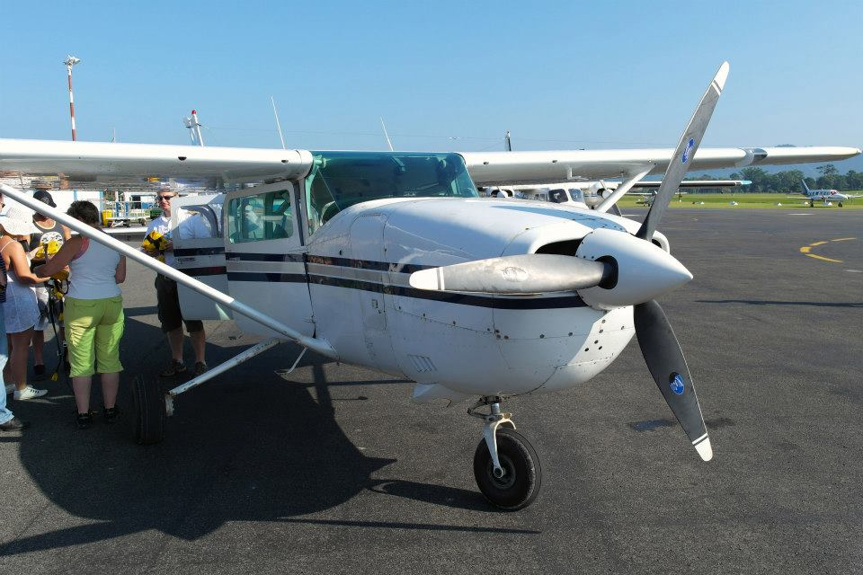 A small plane is grounded as a group of tourists chat around it.