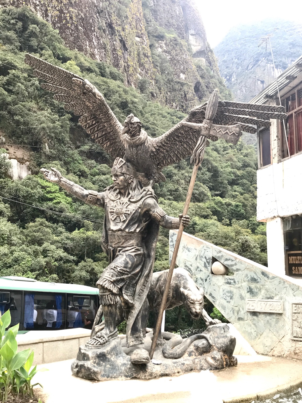 A majestic statue of an Inca warrior with a large bird of prey on his shoulders and. a sphere in his hand in Aguas Calientes, Peru