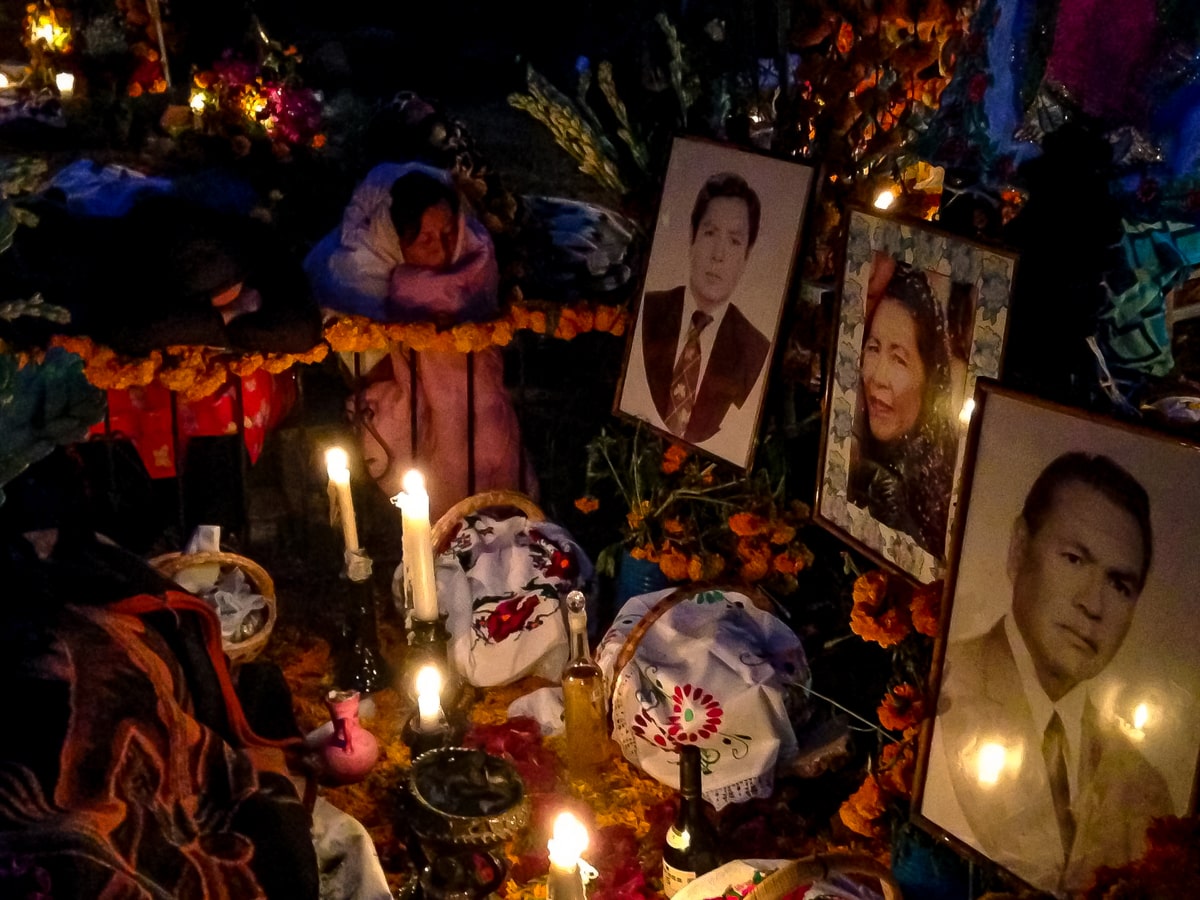 Pictures of passed loved ones lie on the gravestones in Janitzio Island during a Dia de Muertos procession 