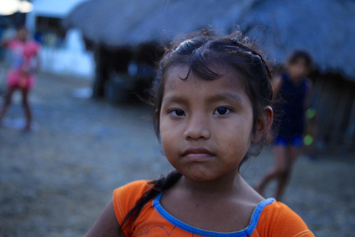 A young girl in an orange top portrait photo.