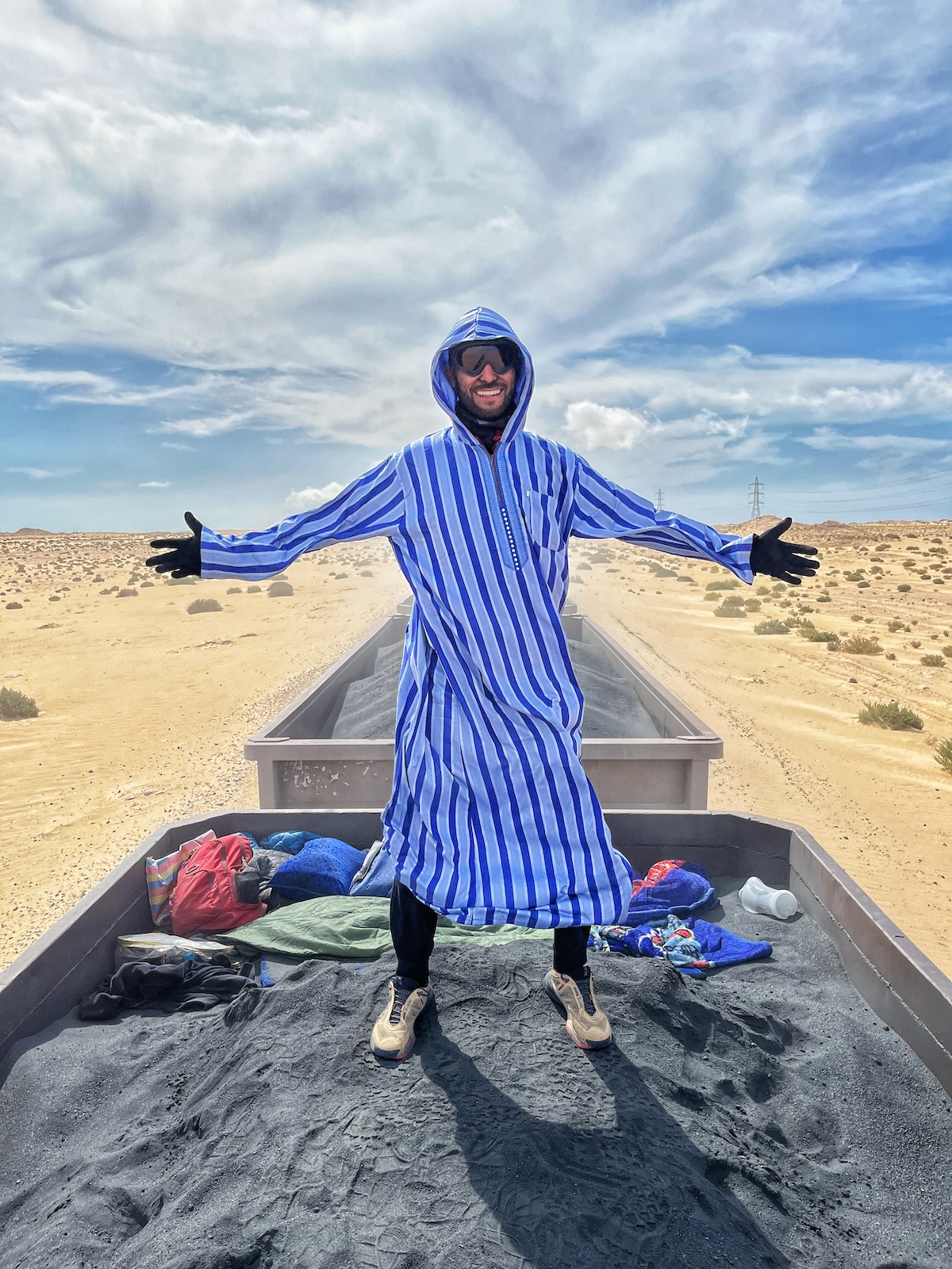A man poses while riding on the iron ore train in Mauritania 