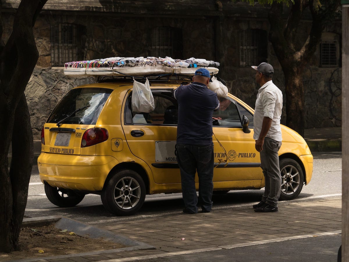 Taxi driver arranging sunglasses shades display board on car cab roof in Medellin Antioquia Colombia in South America