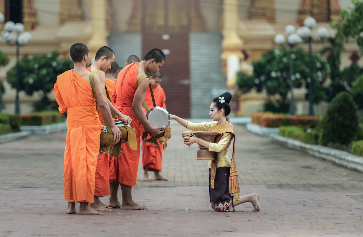 A woman gives food offerings to Buddhist monks in Vientiane, Laos