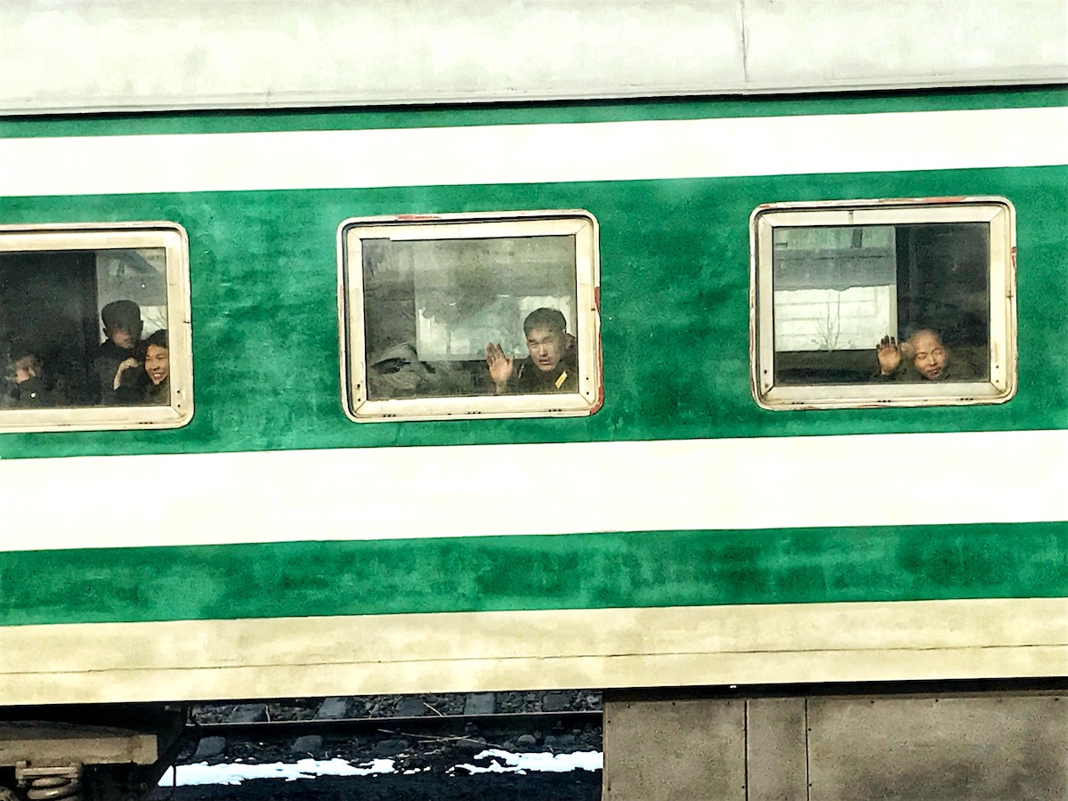 North Korean people waving through a train window at tourists