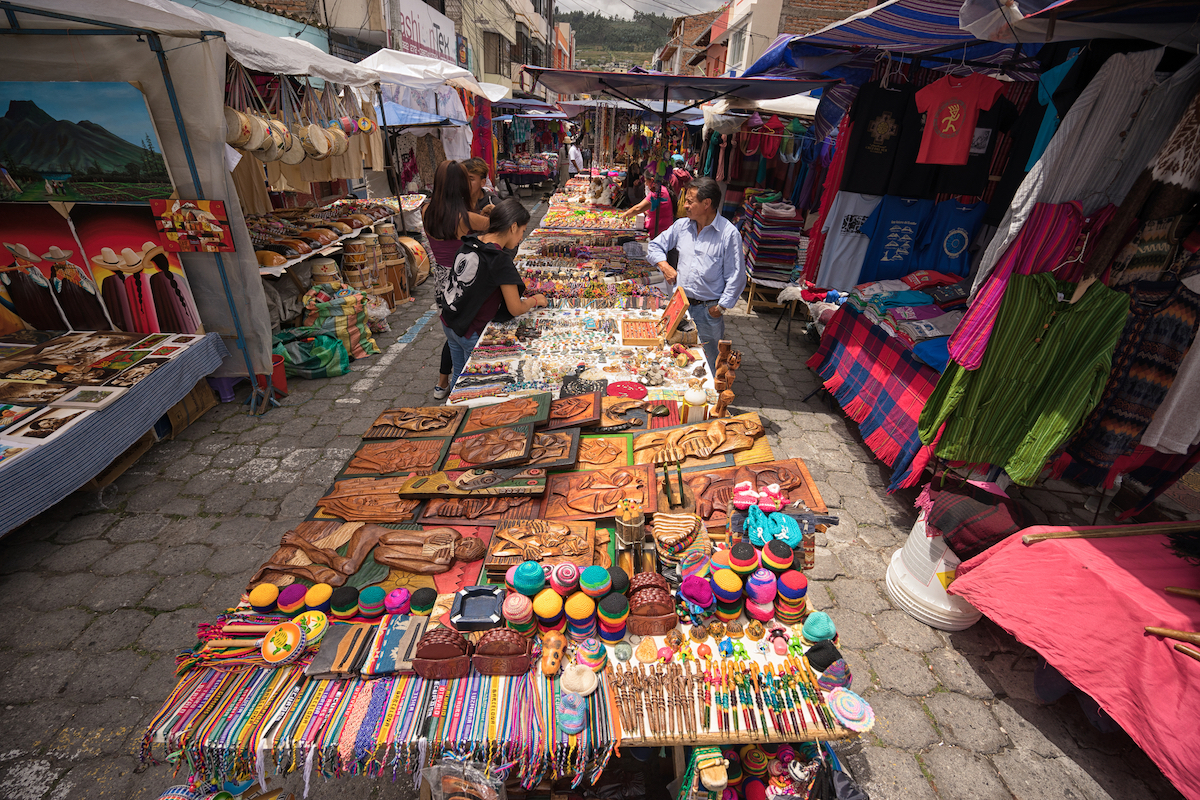 indigenous quechua people selling artisan gifts on stands set up on the street in the Saturday market