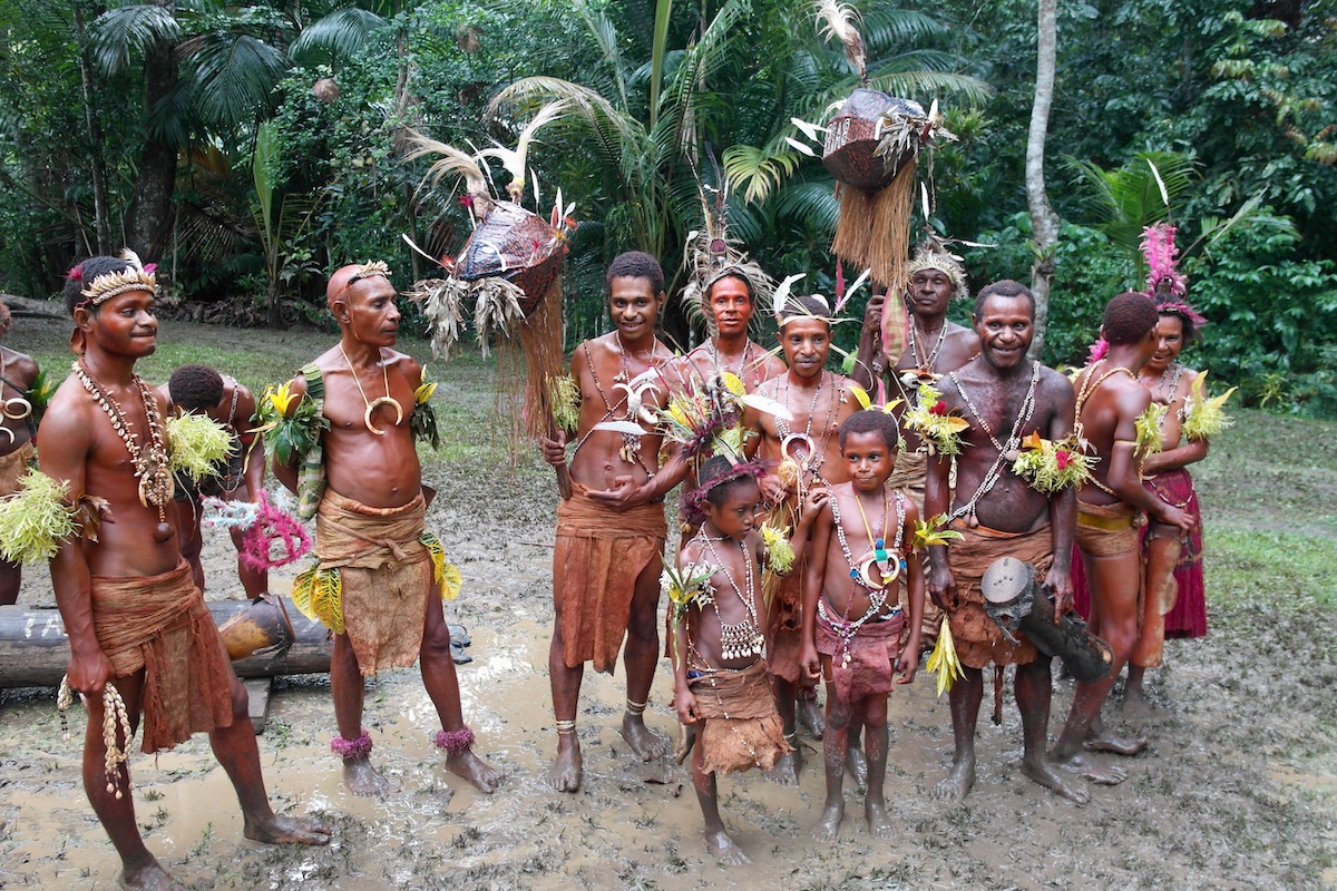 A Papua New Guinea tribe adorned in native attire in the muddy rainforest
