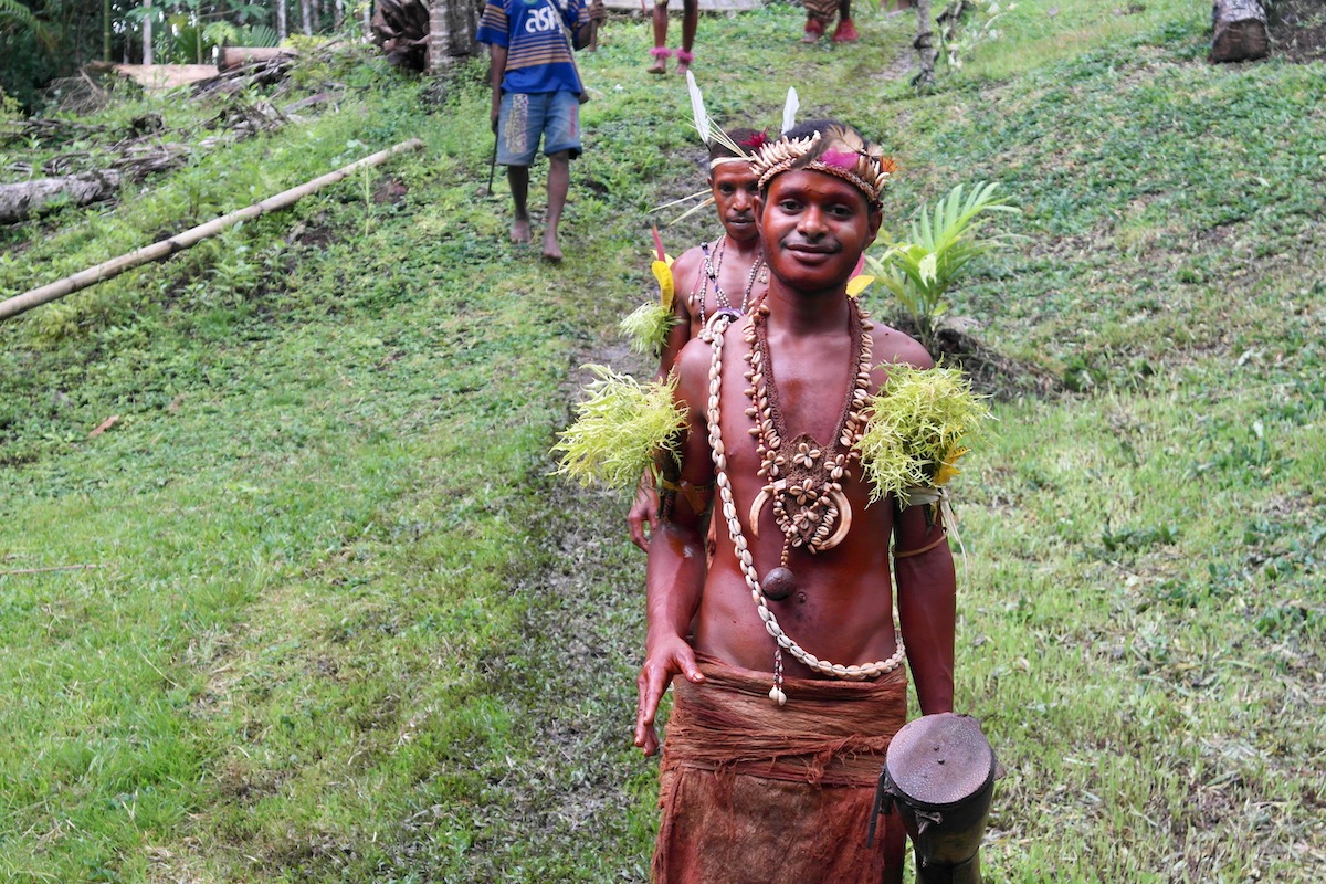 Two tribesman smile as they walk in the Papua New Guinea rainforest