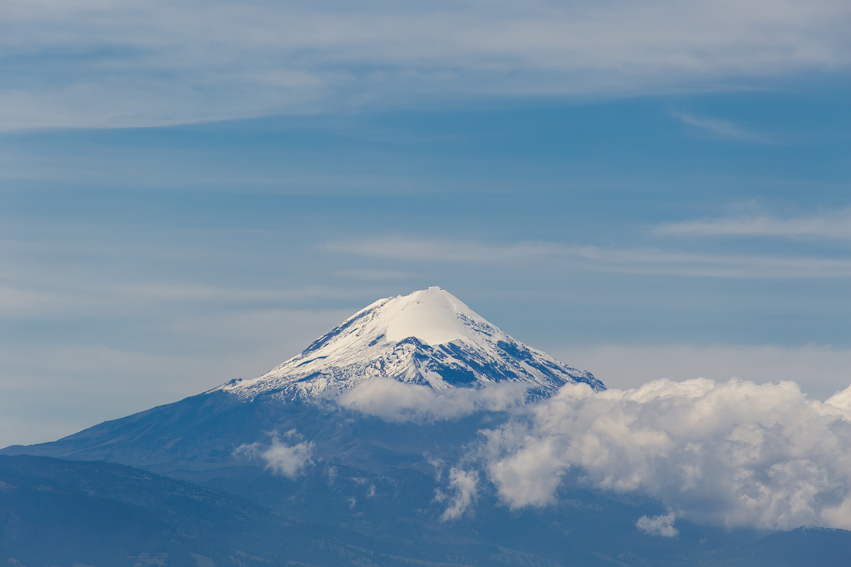 A snow-capped mountain peaks out of the clouds.