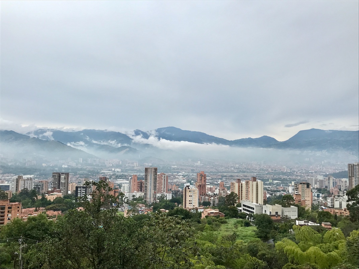 A bustling city overlooks green landscapes and misty mountains during the day in Medellin, Colombia. 