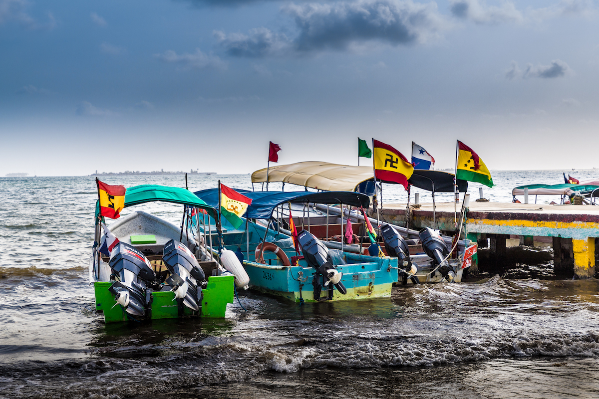 Parked up small boats with colourful flags raised high on each one.