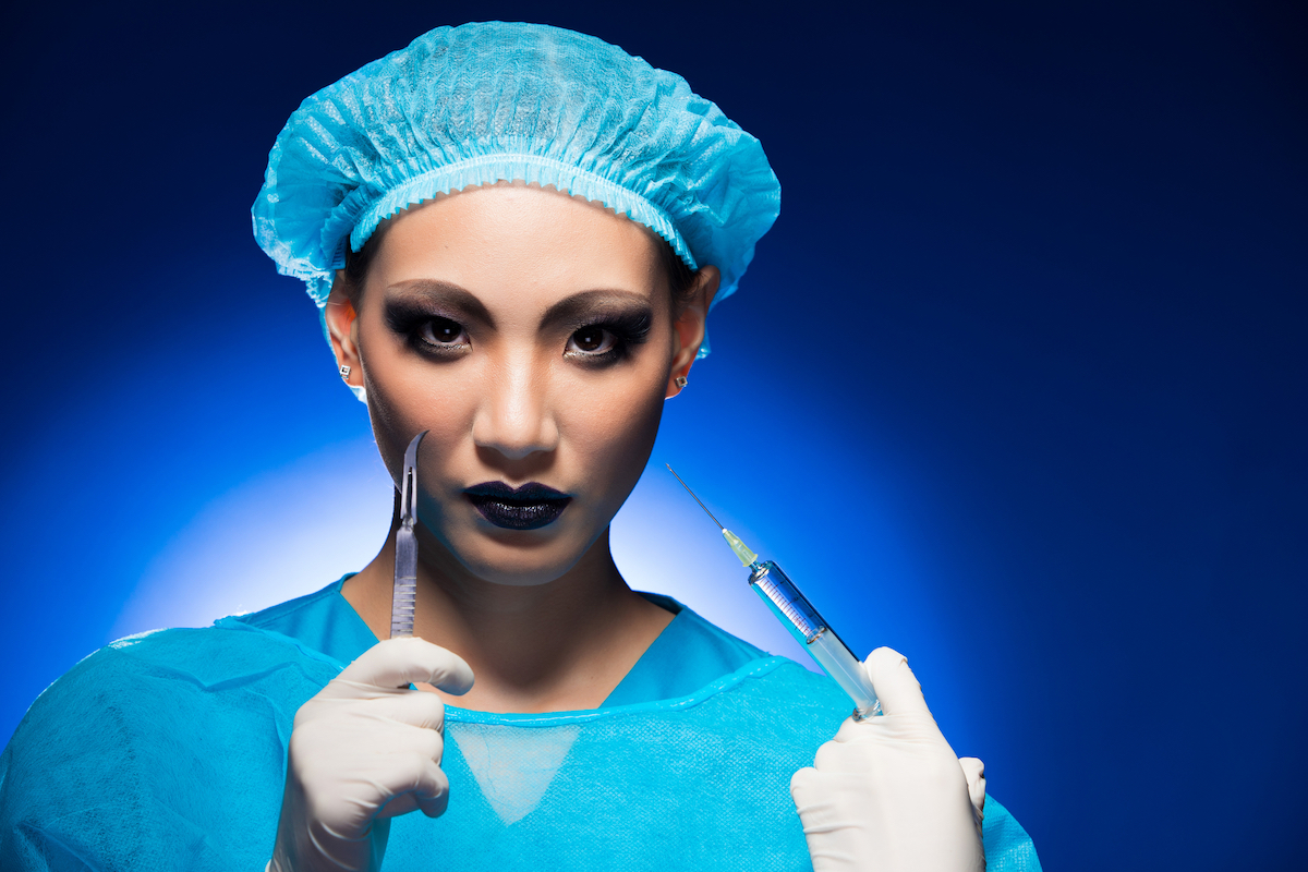 A plastic surgery Doctor or Nurse in a hygiene suit, cap, glove, syringe and surgical knife acts scary
