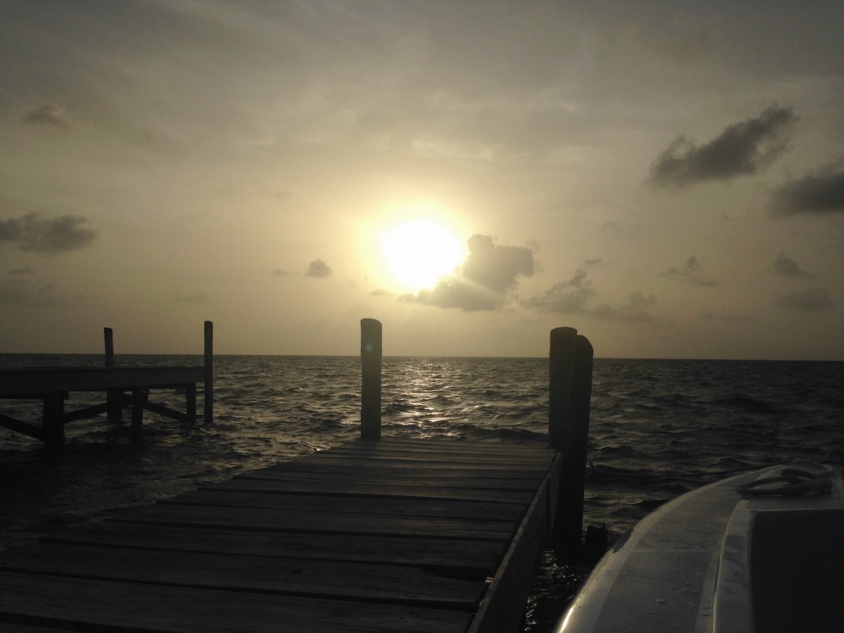 A view from the sea dock of the sun rising behind a cloud in Caye Caulker, Belize