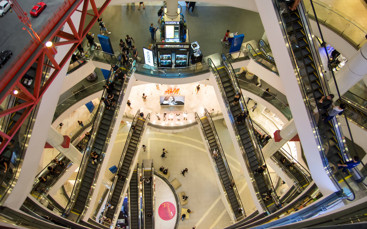 A tall shopping mall top view with many people inside.
