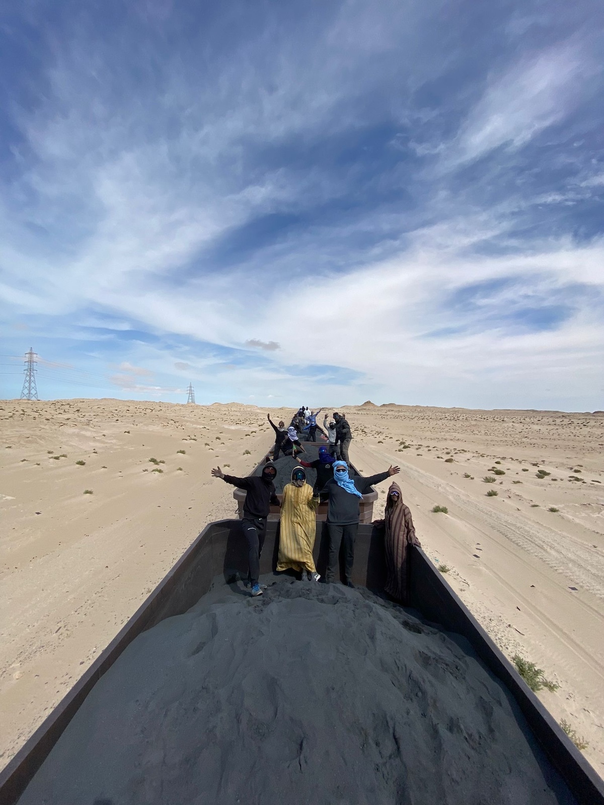 Tourists in the Sahara Desert of Mauritania hitchhike on top of the famous iron ore train