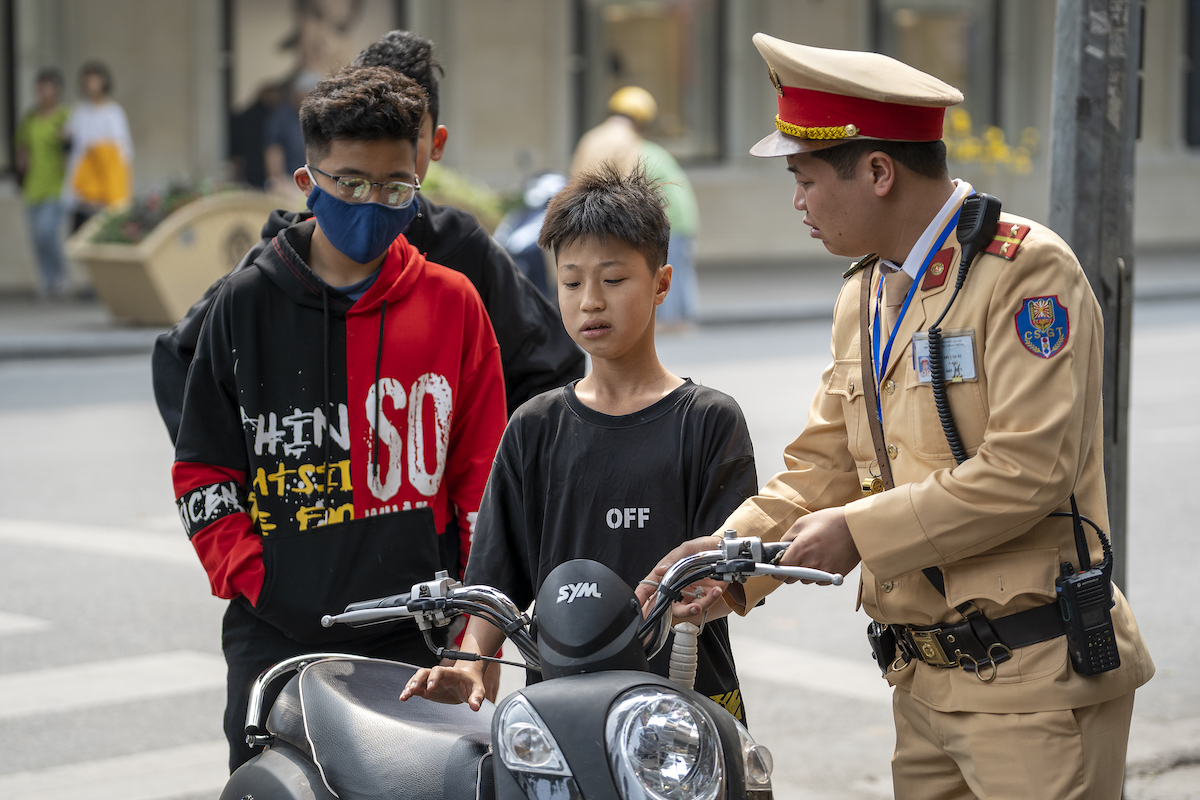 A Vietnamese police officer stopped a motorbike driver boy for violating traffic rules on the street in the old town of Hanoi, Vietnam