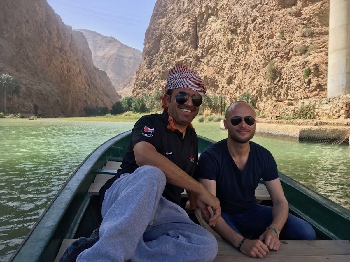 Two men laugh on a small boat on Wadi Bani Khalid on a day trip from Oman. 