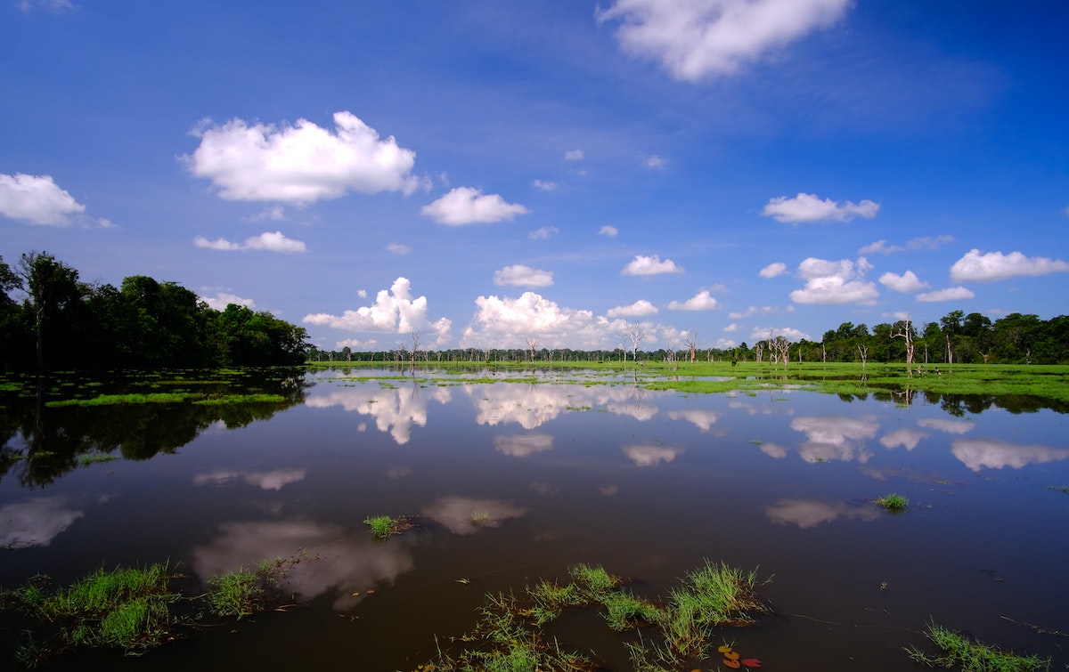 The cloudy sky reflects off a large lake. 